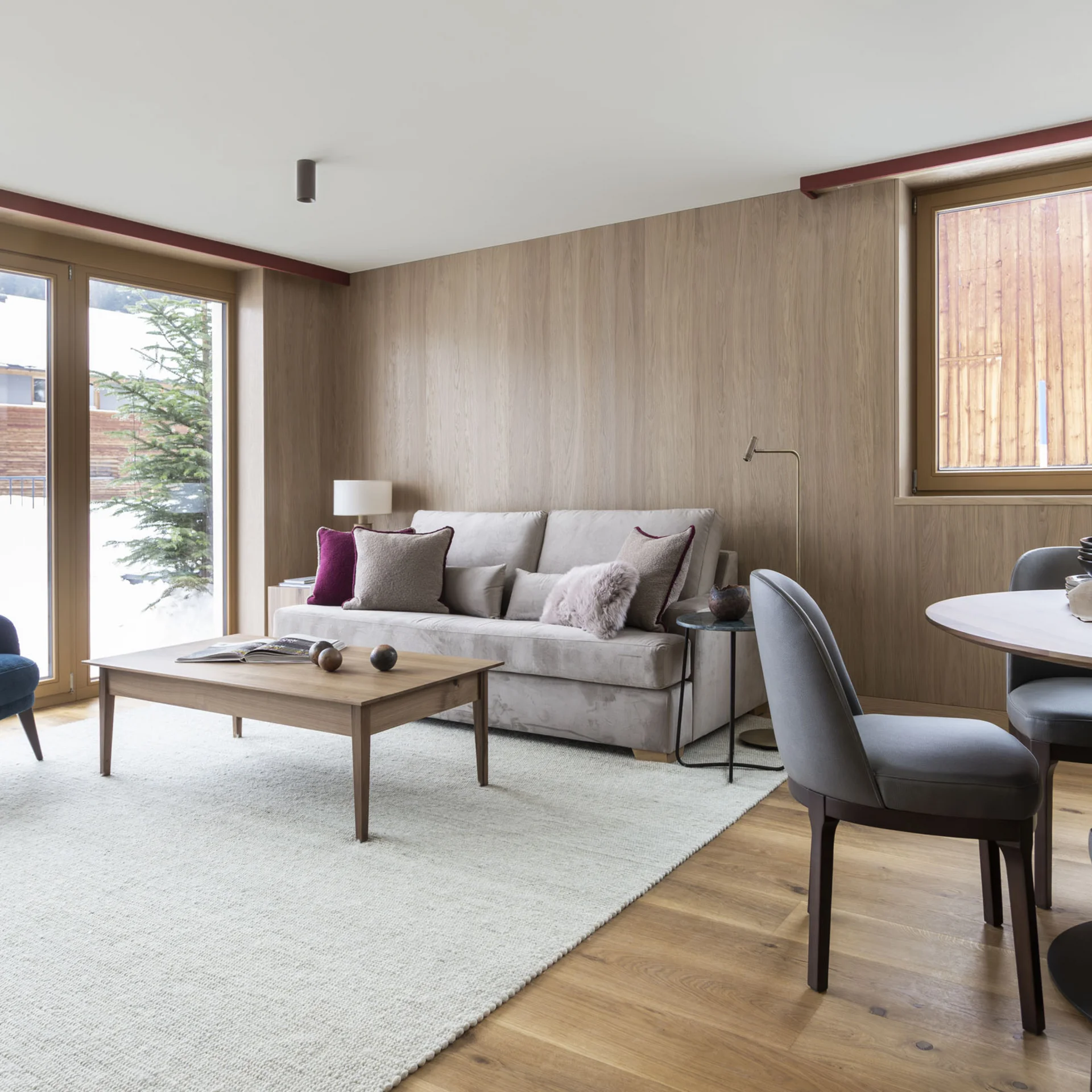 Ihr Hotel in Lech am Arlberg. Das Sunora. Gemütliches Wohnzimmer mit Sofa, Sesseln, Esstisch und großen Fenstern mit Bergblick