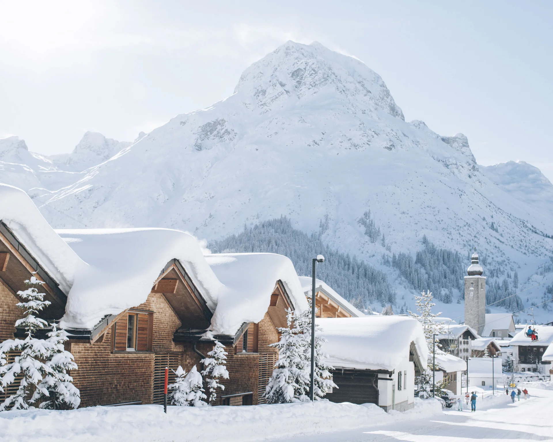 Ihr Hotel in Lech am Arlberg. Das Sunora. Schneebedeckte Häuser unter einem verschneiten Berg im Winter