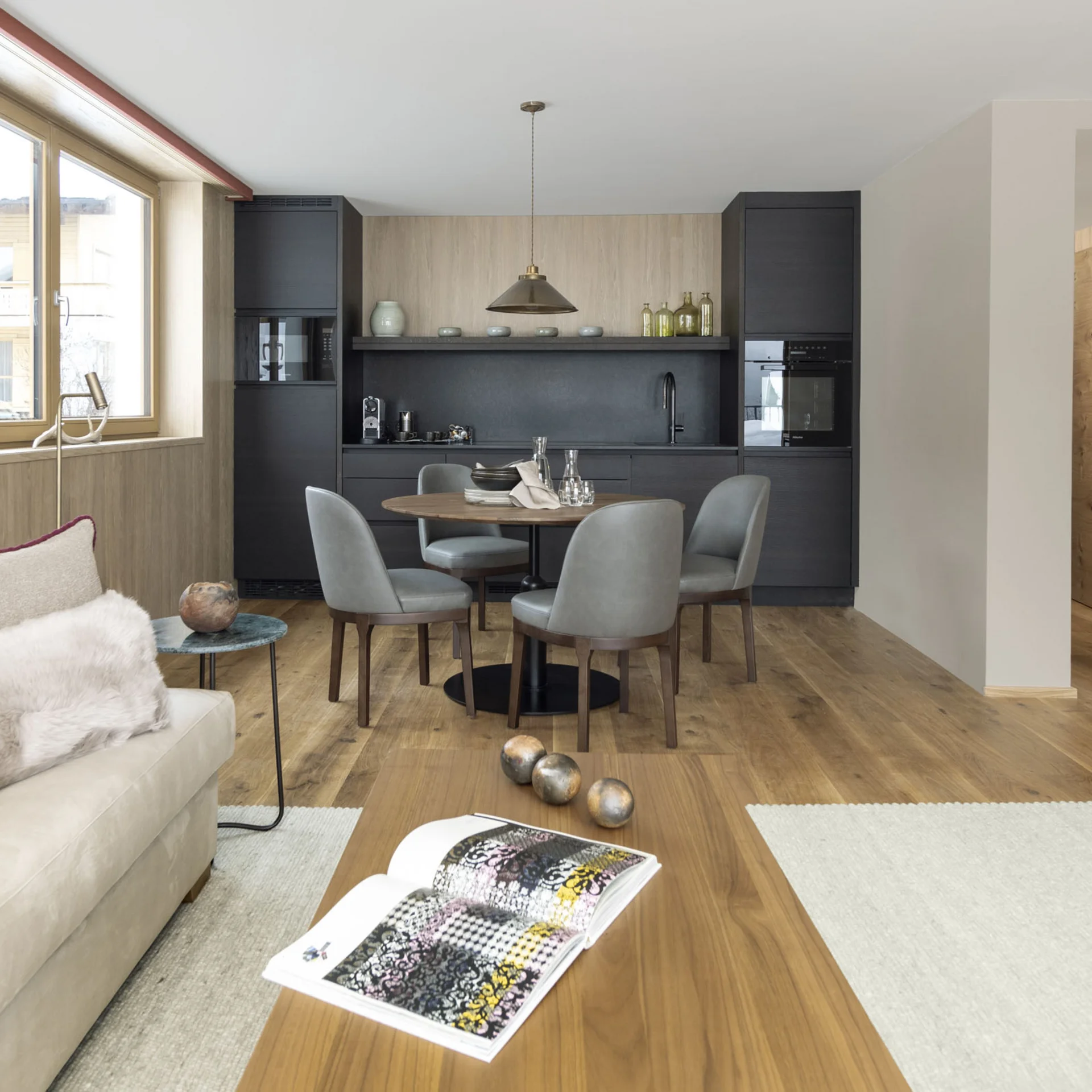 Ihr Hotel in Lech am Arlberg. Das Sunora. Moderner Wohn- und Essbereich mit schwarzer Küche und Holzboden