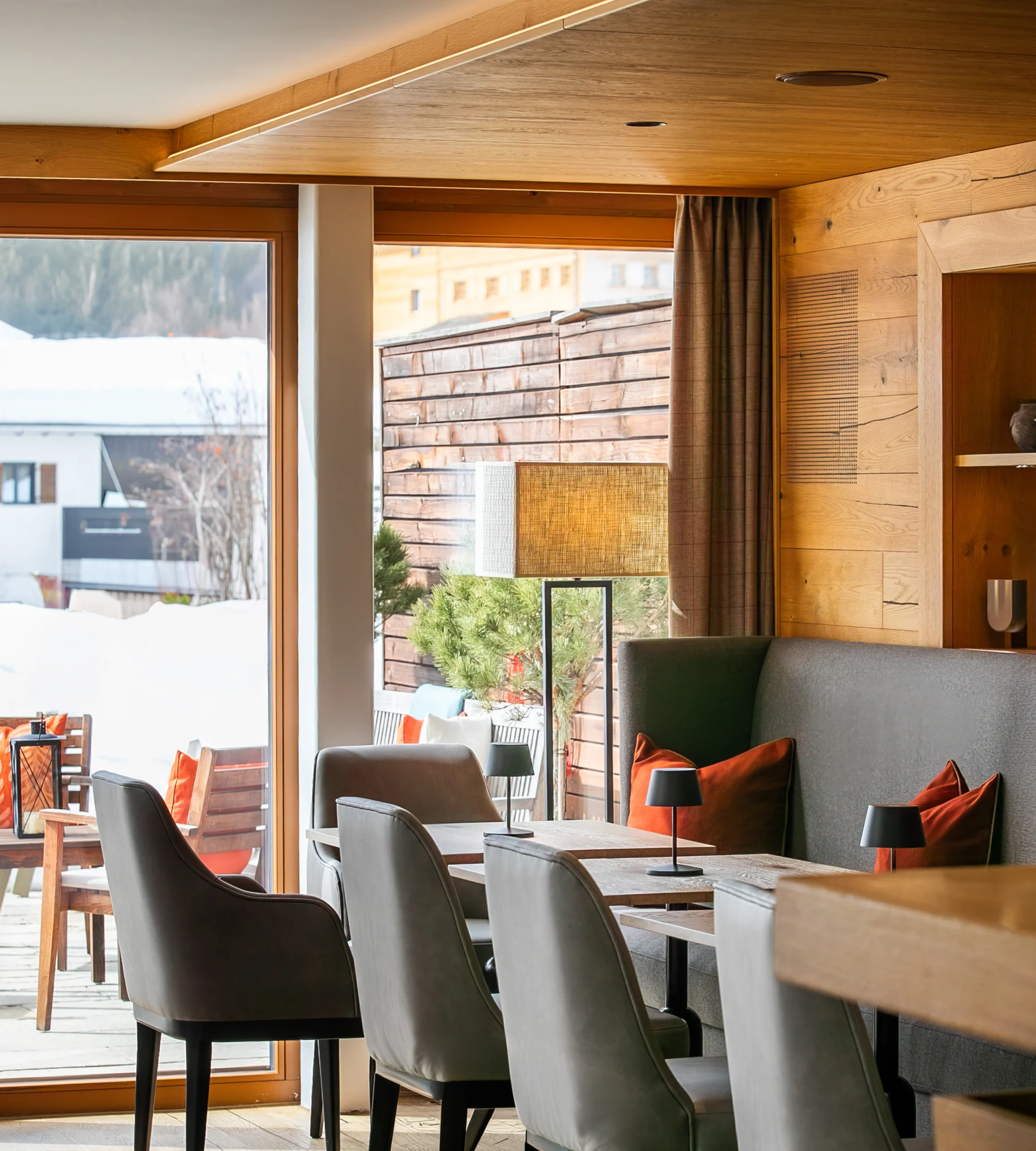 Ihr Hotel in Lech am Arlberg. Das Sunora. Moderner Gastraum mit Holzdecke und Sitzbereich neben großen Fenstern im Winter