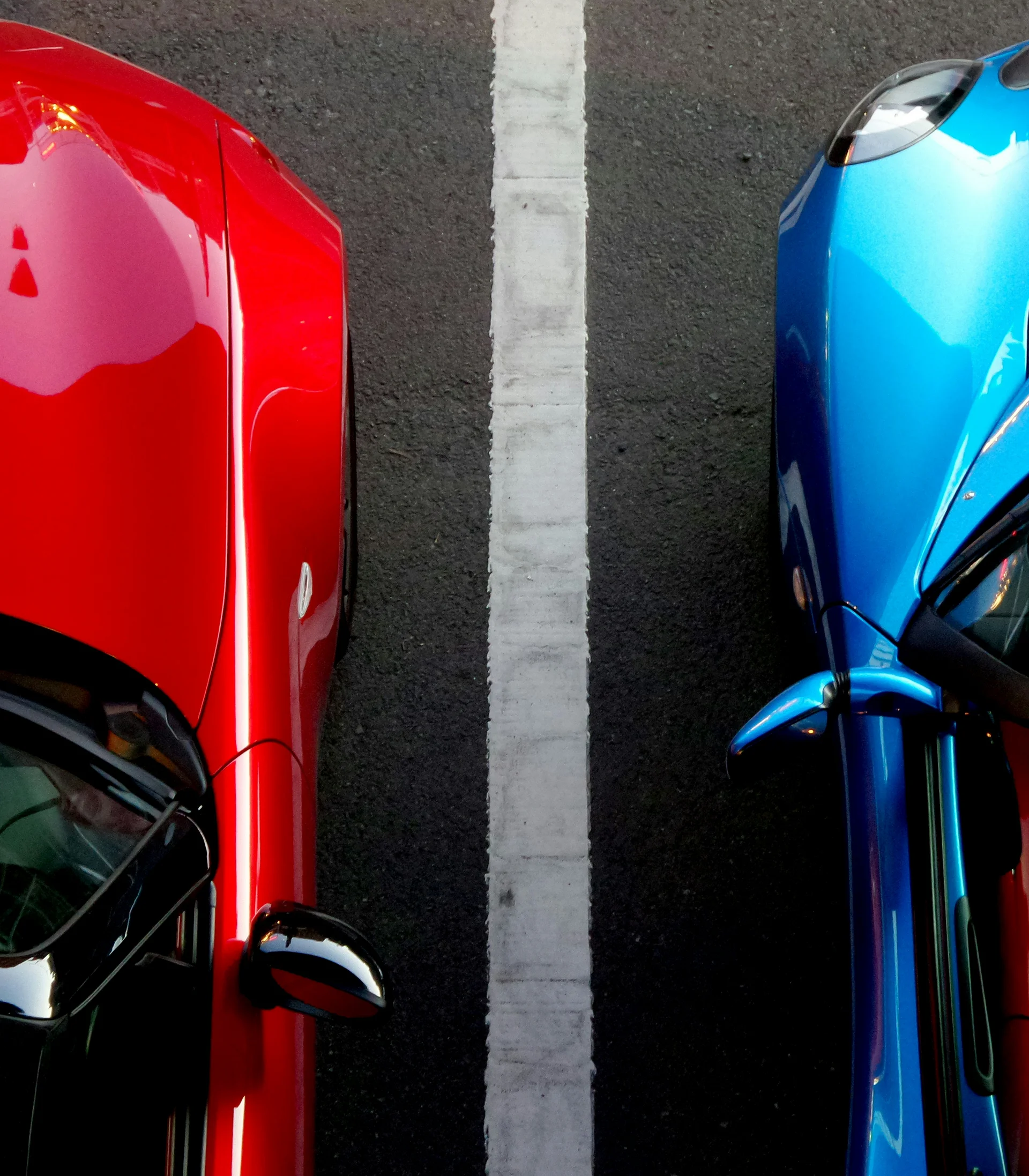 Ihr Hotel in Lech am Arlberg. Das Sunora. Nahaufnahme von zwei nebeneinander parkenden roten und blauen Autos