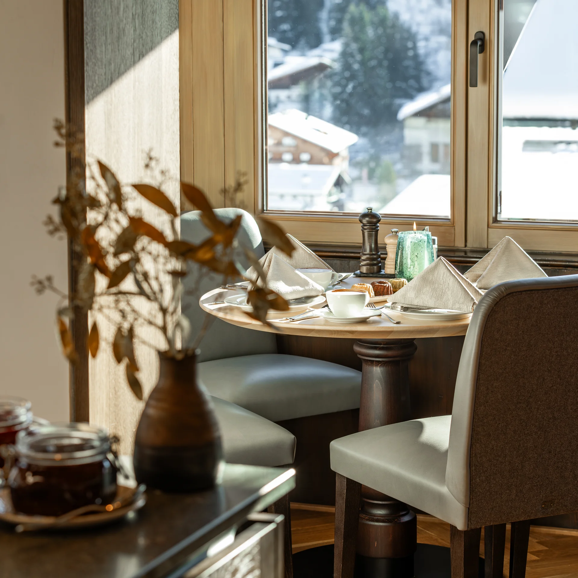 Ihr Hotel in Lech am Arlberg. Das Sunora. Gemütlicher Esstisch mit Fensterblick auf verschneite Häuser