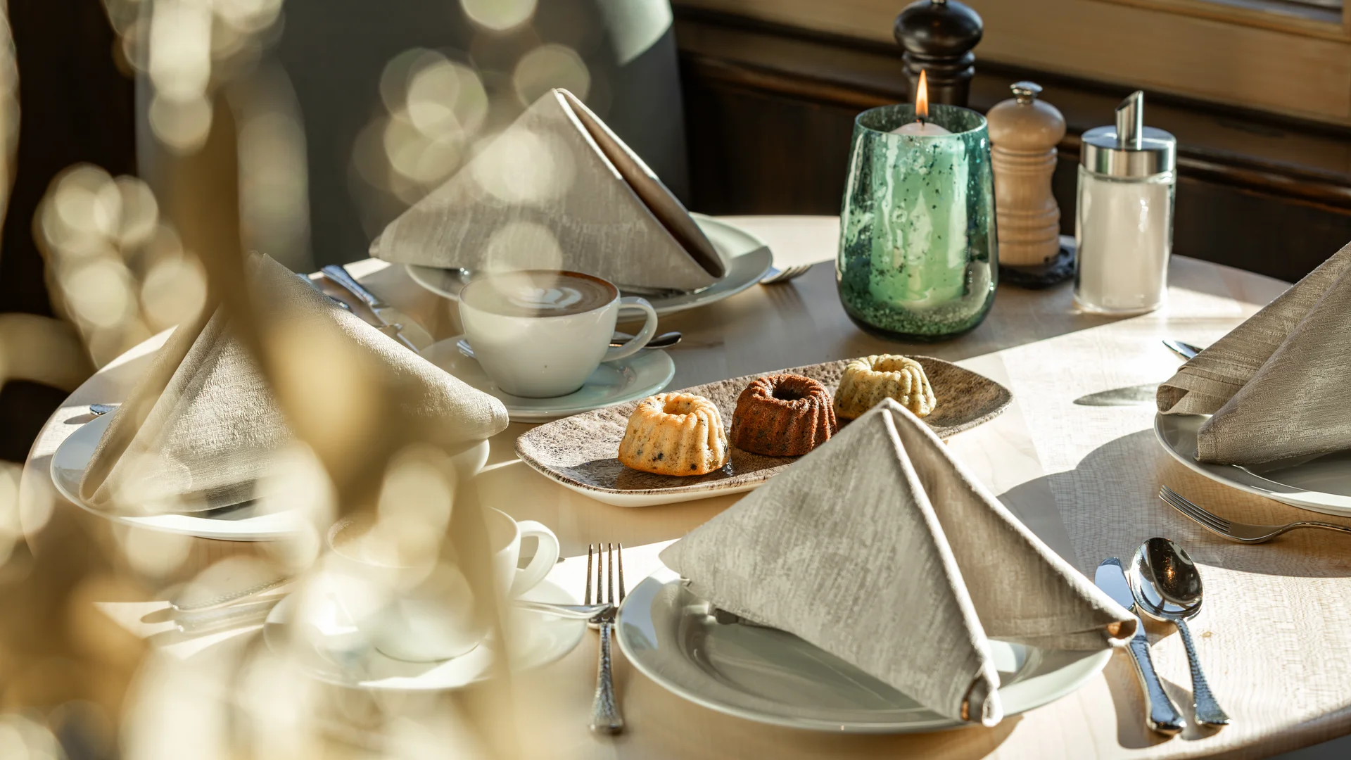 Ihr Hotel in Lech am Arlberg. Das Sunora. Eingedeckter Tisch mit Kaffee, Kuchen, Kerze und Gewürzen im Restaurant