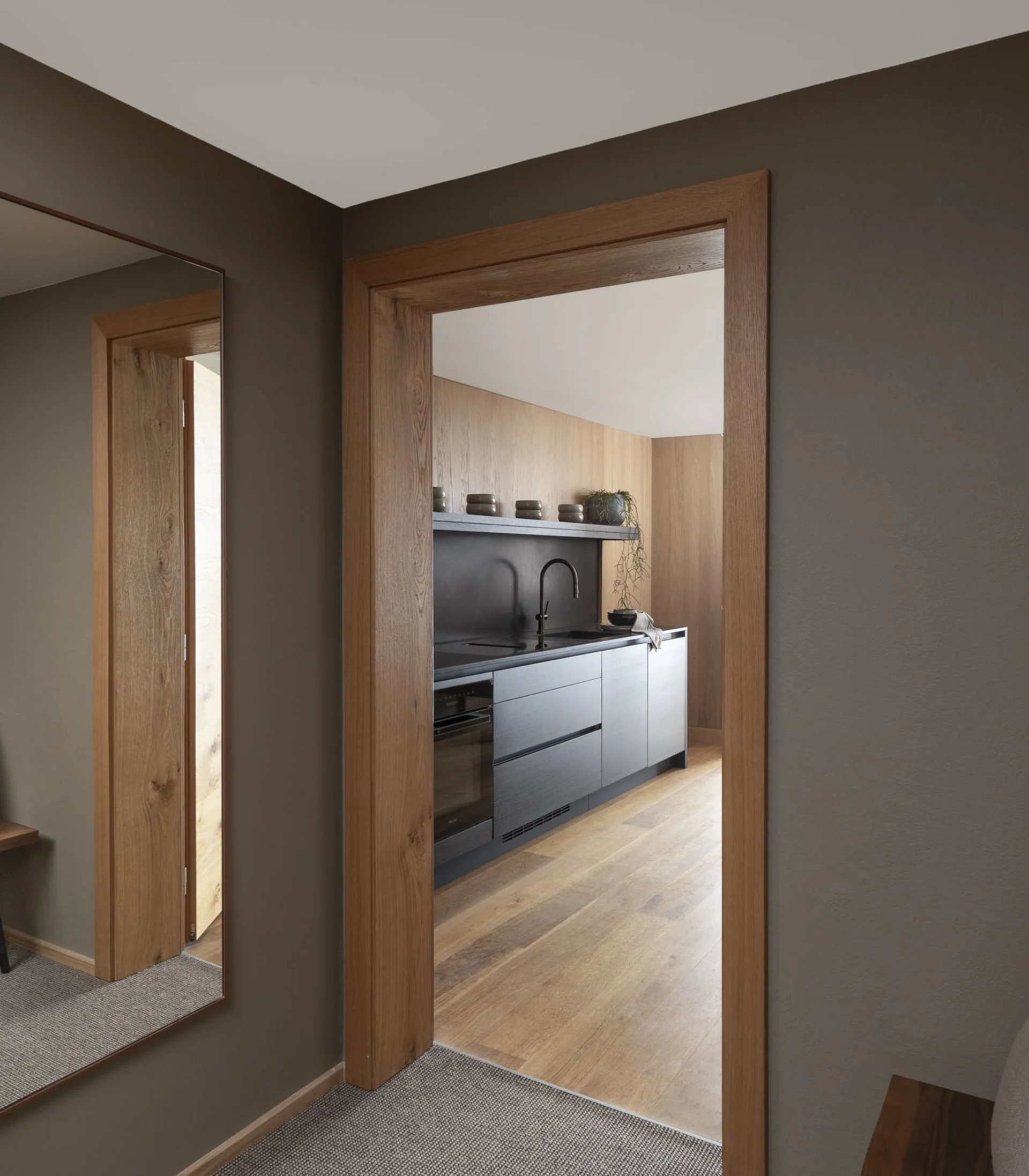 Ihr Hotel in Lech am Arlberg. Das Sunora. Flur mit großem Spiegel neben Holztür zum modernen Küchenbereich