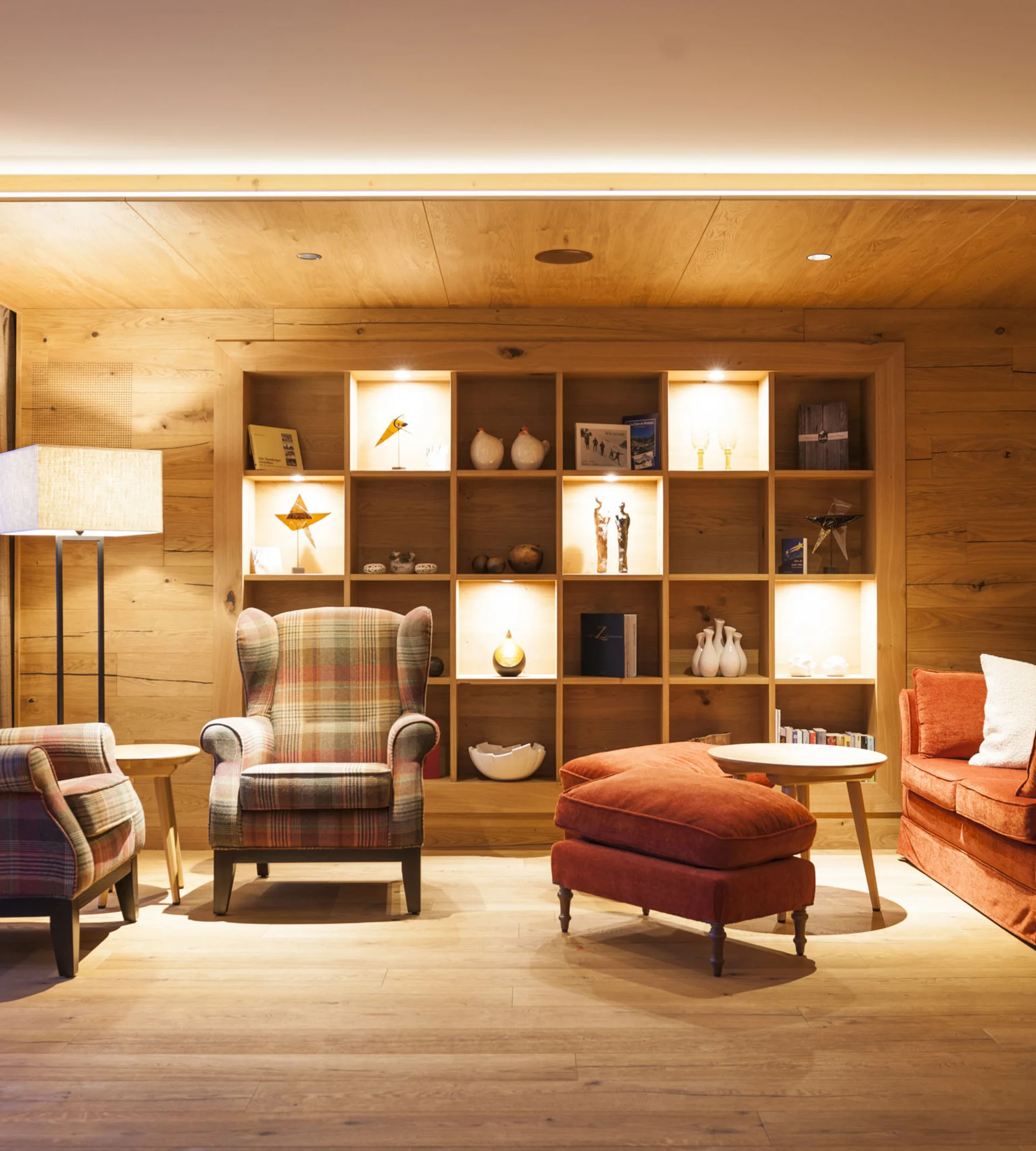 Ihr Hotel in Lech am Arlberg. Das Sunora. Gemütliches Wohnzimmer mit Holzwänden, Sessel und Regal mit Dekoration