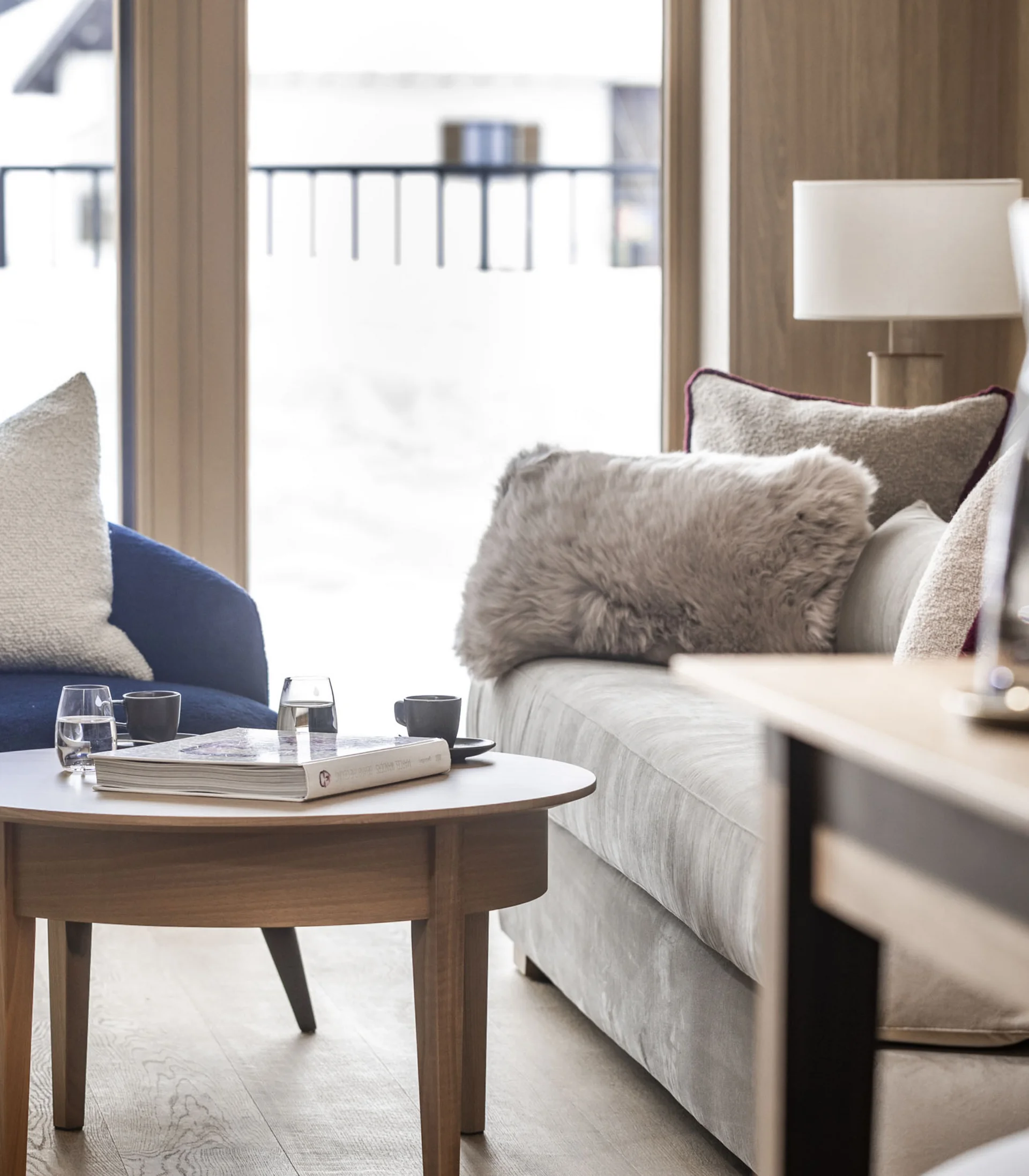 Ihr Hotel in Lech am Arlberg. Das Sunora. Gemütlicher Wohnbereich mit Sofa, Sesseln und einem Holztisch vor Fenster