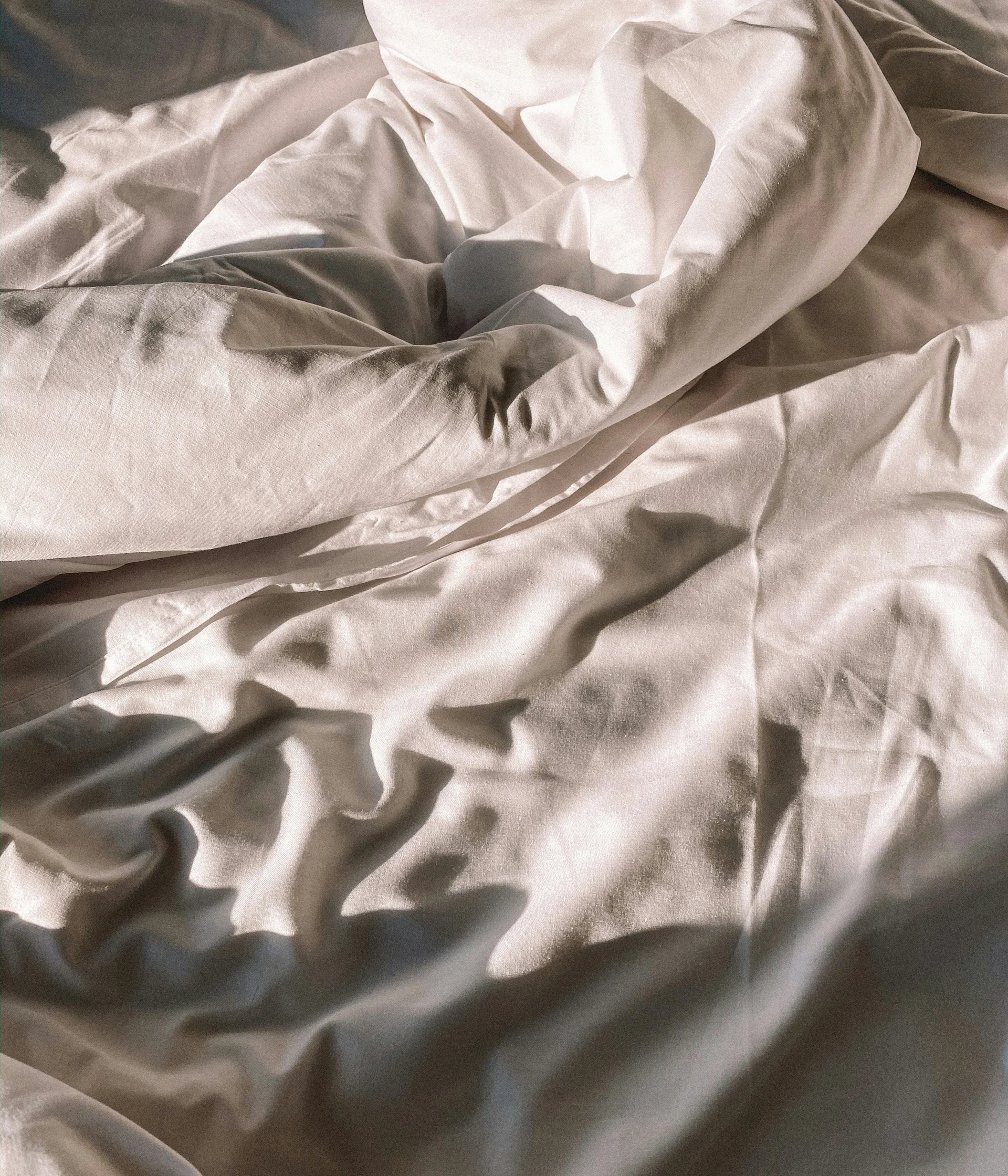 Ihr Hotel in Lech am Arlberg. Das Sunora. Weißes zerknittertes Bettlaken mit Sonnenlicht und Schatten