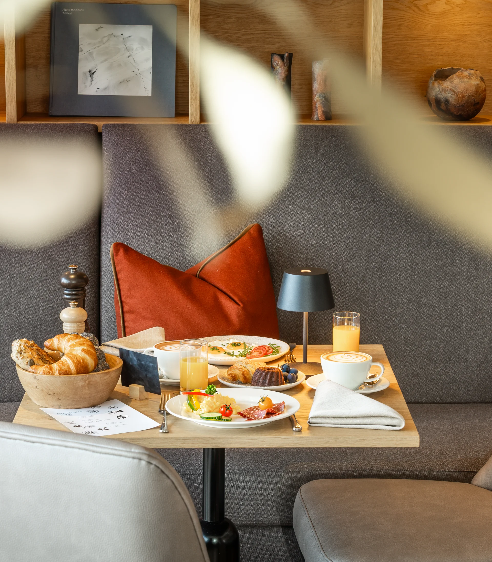 Ihr Hotel in Lech am Arlberg. Das Sunora. Gemütlicher Frühstückstisch mit Croissants, Eiern und Getränken in modernem Café